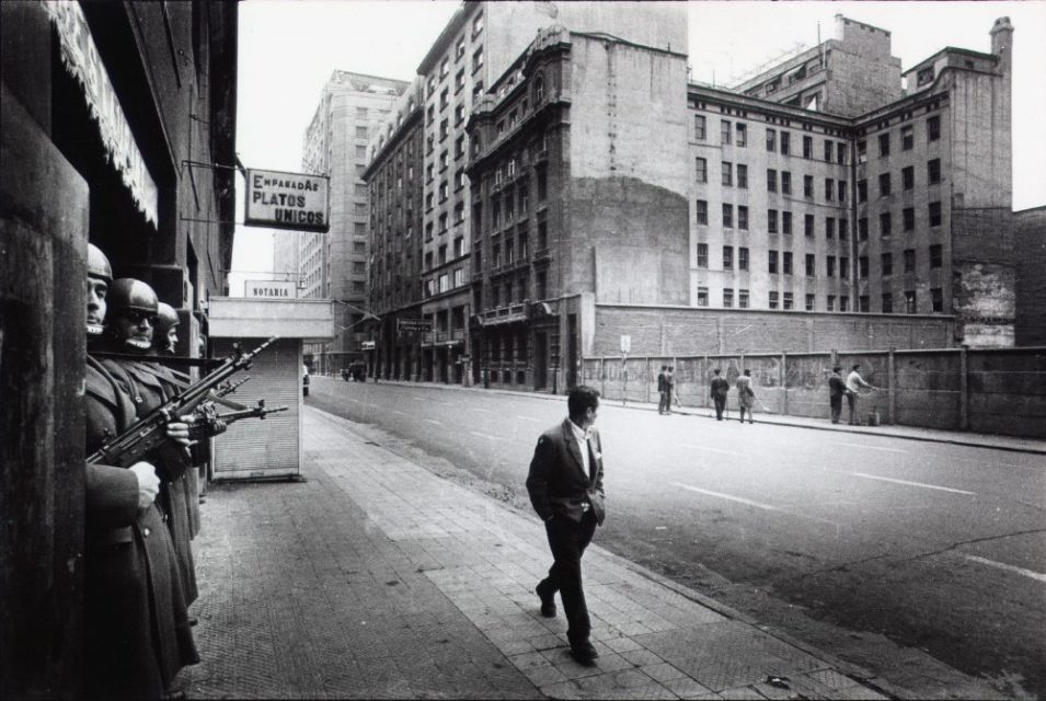 Chili, Santiago, september 1973. People are being forced to remove revolutionary slogans from buildings while militaries are watching.