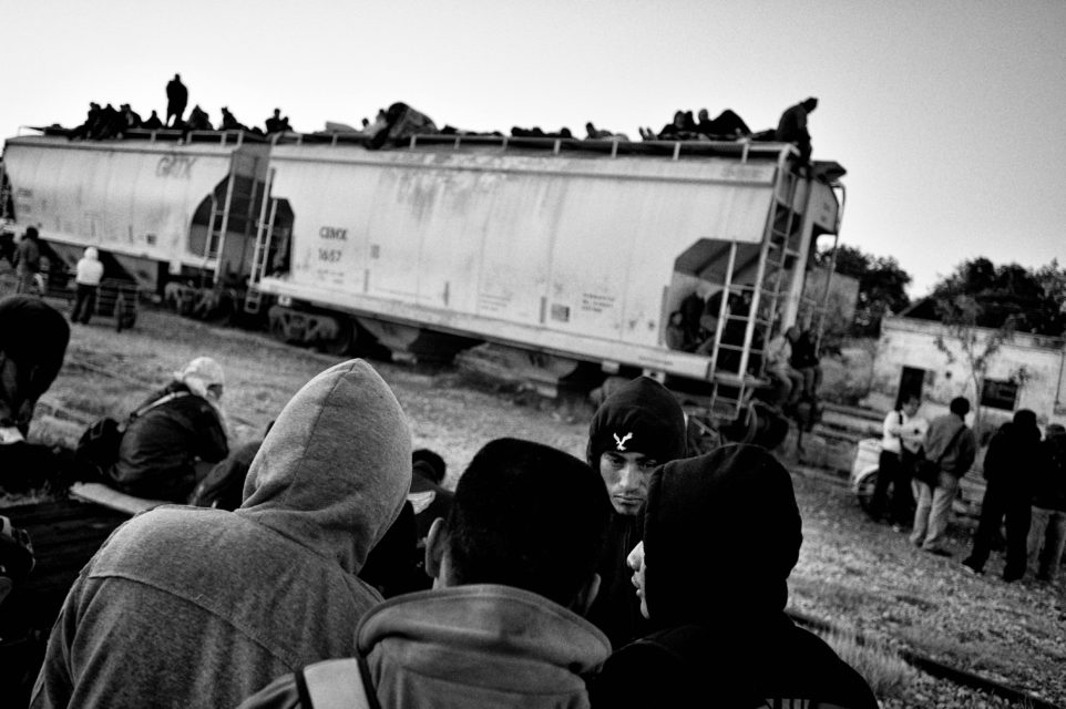 Migrants from central America are waiting in Arriaga for the cargo train to arrive. They will travel on the roof of the train to the US.